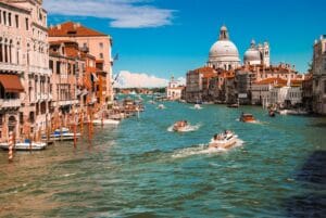 The Grand Canal in Venice, Italy, featuring gondolas and historic buildings. Organized by Europa Travel Hub.