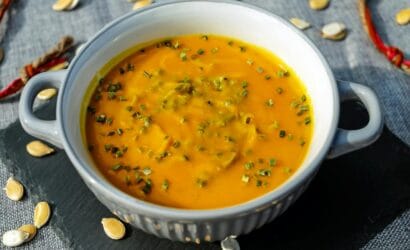 Warm and creamy pumpkin soup garnished with fresh herbs, perfect for a cozy meal.