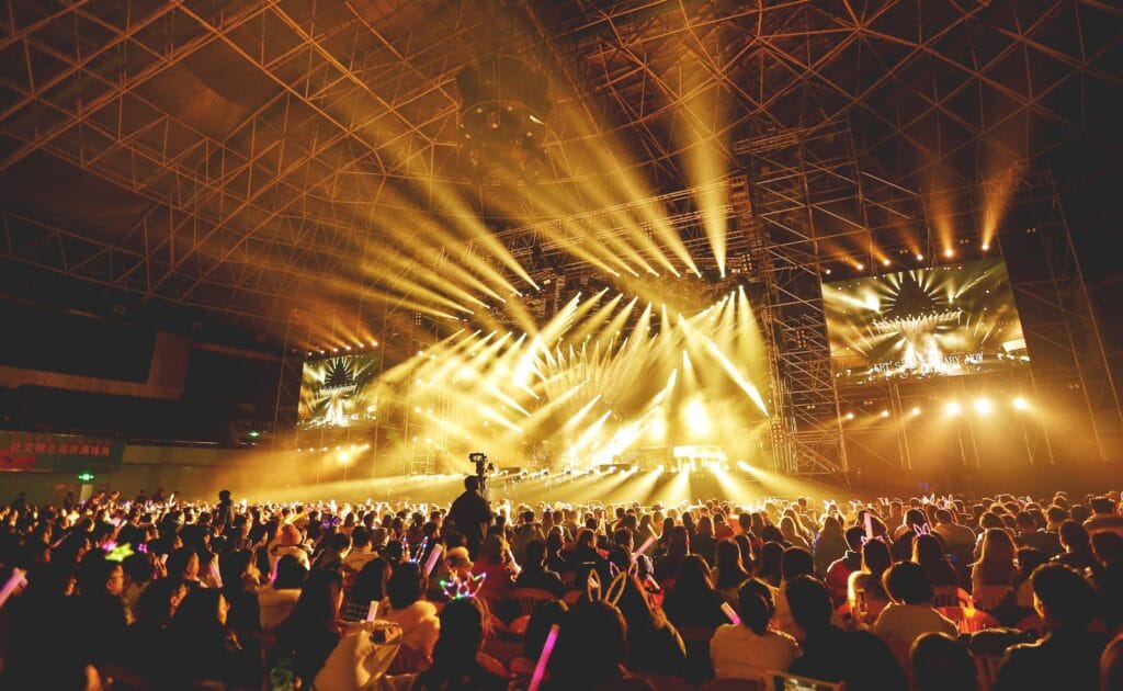 Dynamic concert scene with vibrant crowd and dazzling stage lights indoors.