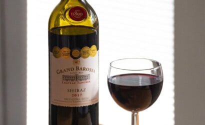 A glass of Barossa Valley Shiraz wine with a deep red hue, set against the backdrop of vineyards, curated by Europa Travel Hub.