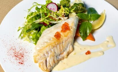 A perfectly grilled Barramundi fillet served with fresh herbs and a side of vegetables, typical of Northern Australia’s cuisine.