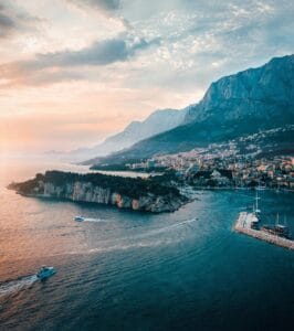 Aerial view of Makarska, Croatia, showcasing the stunning Adriatic coastline, nearby islands, and majestic Biokovo Mountains at sunset.